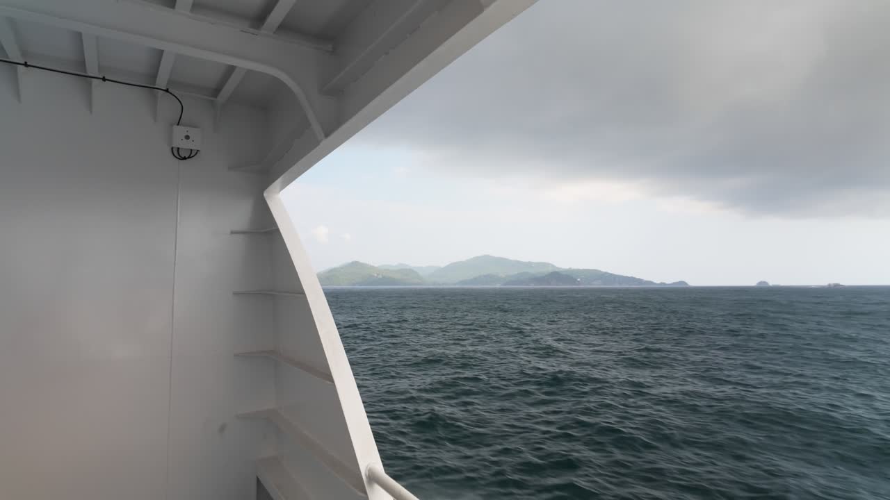 Blick vom Fährdeck auf ferne grüne Inseln, die sich über unruhiges Meerwasser nähern.
