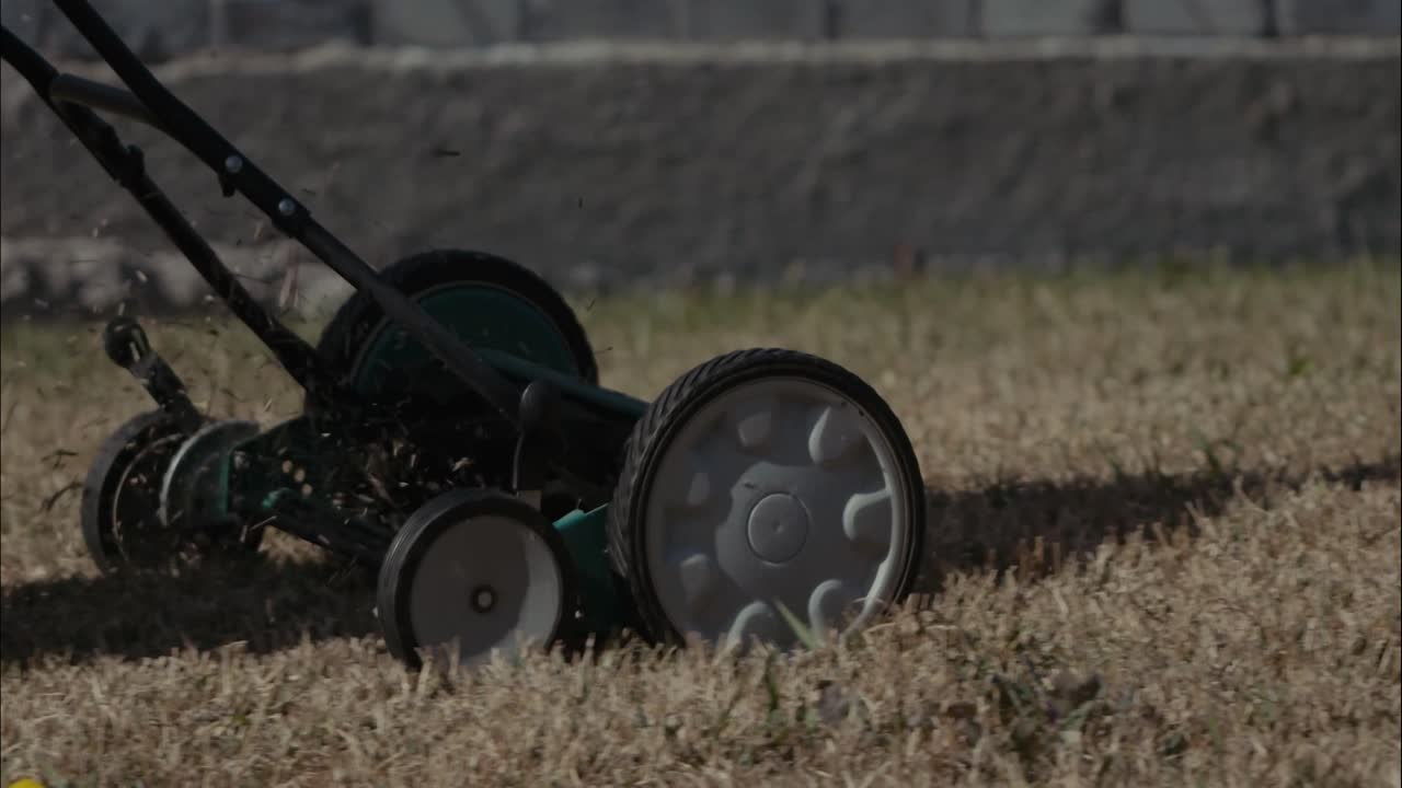 una cortadora de césped manual que se empuja sobre un césped irregular