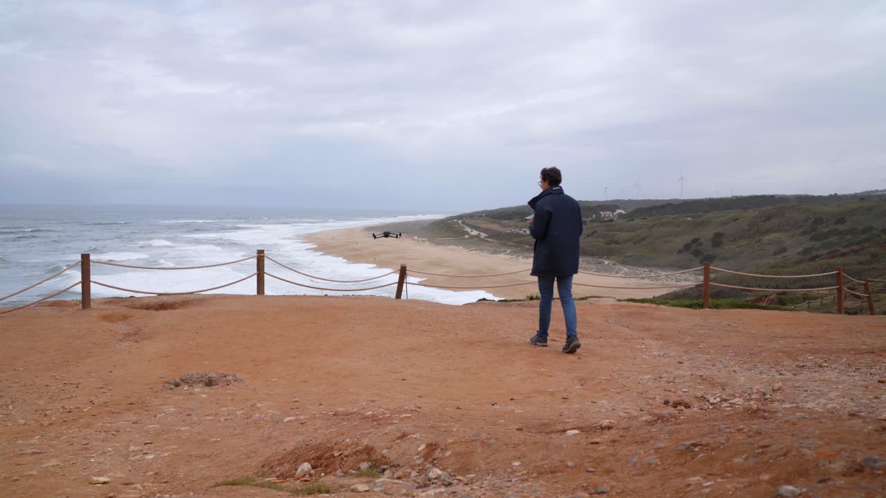 un joven viajero volando y despegando un avión no tripulado en una pintoresca playa de nazare en portugal