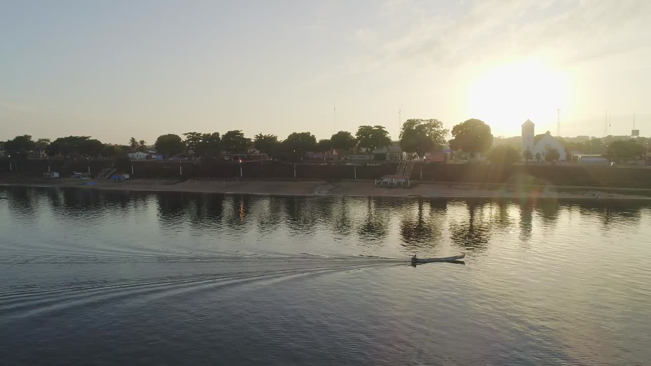 Sliding aerial of river with small boat going and sun on the background