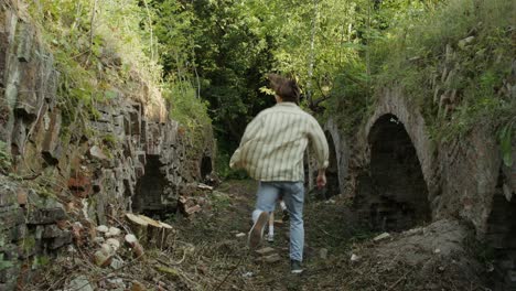 people walking through abandoned ruins in a forest