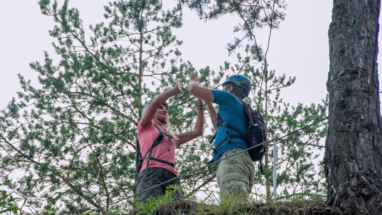 Two trekkers hit high five and indicate something interesting. Low angle