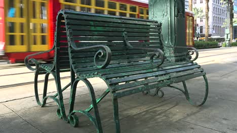 a red trolley passes a green bench in new orleans