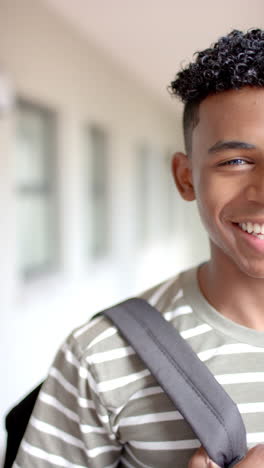 vertical video: smiling teenager with backpack in school hallway, ready for class
