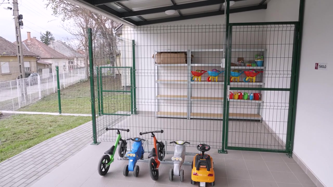 Área de armazenamento externa em uma creche com brinquedos de montar infantis e acessórios para brincar na areia.