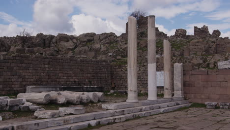 ancient pillars in front of a stone wall in pergamum