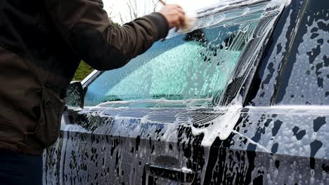 cleaning around car windows with a detailing brush