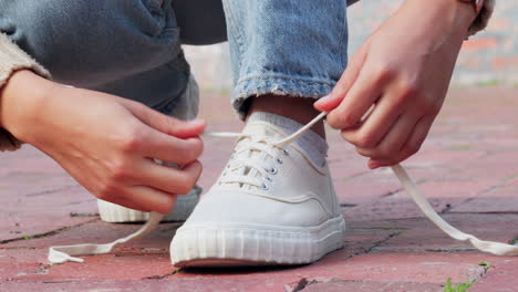 mãos amarrando tênis sapatos laços nos pés na cidade