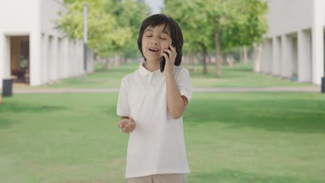 행복한 인디언 소년은 공원에서 전화로 이야기하고 있습니다.