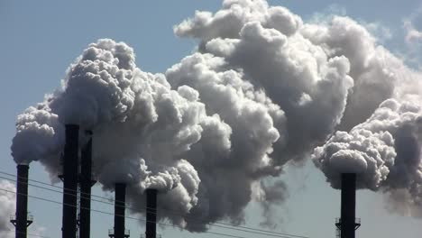 a power plant with smokestacks belches smoke into the air