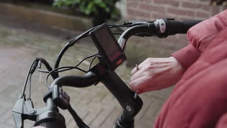 a lady adjusting the tension of a bolt on the steering column of a electric bike to loosen it off enough to change the angle of the handle bars