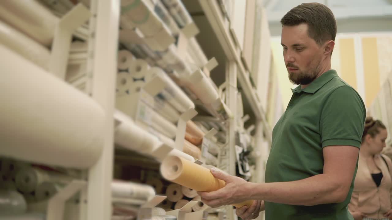 hombre comprando papel tapiz en una tienda de mejoras para el hogar