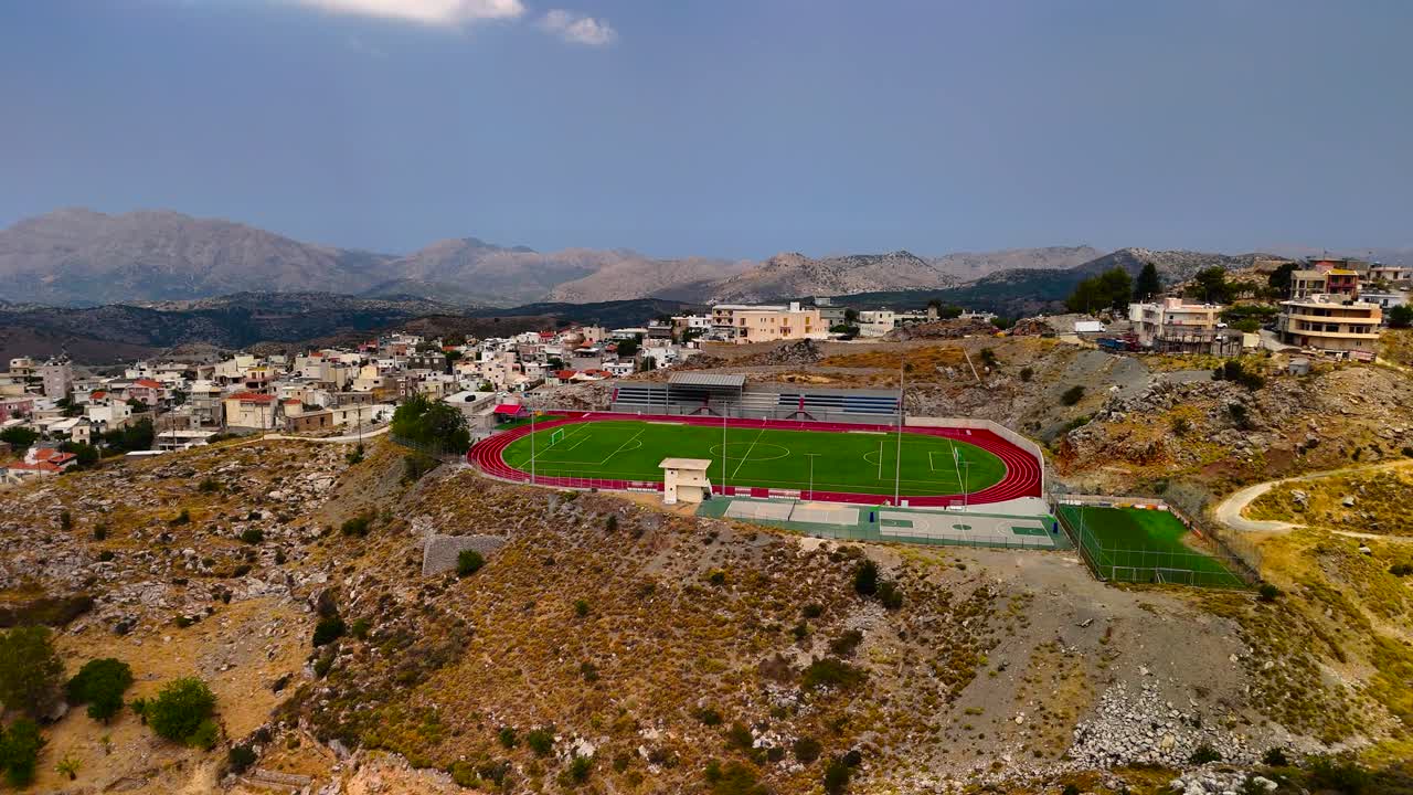 Enjoy the excitement of a soccer match taking place in a picturesque mountain area. The teams compete on a vibrant green field surrounded by stunning natural beauty