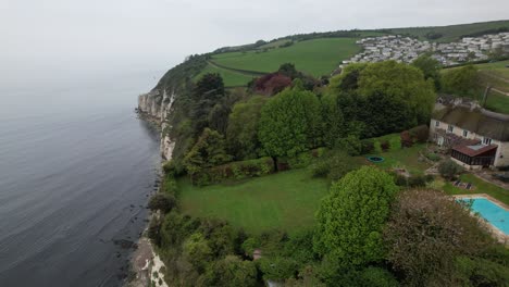 house on edge cliff in devon england drone aerial view