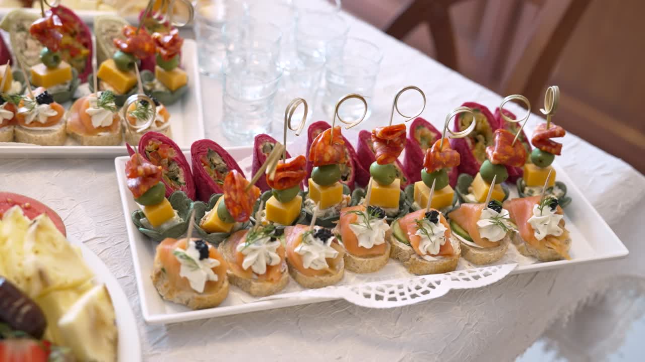 Gli invitati possono gustare diversi stuzzichini presentati su vassoi durante un evento. Questi piccoli assaggi includono verdure, formaggi e carne, disposti in modo accattivante.
