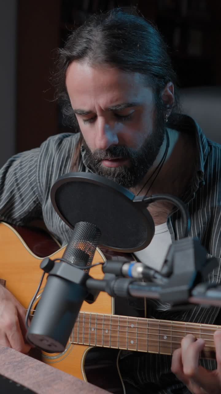 Man Playing Acoustic Guitar and Singing into a Microphone