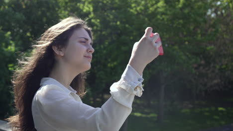 pretty italian woman tourist taking photograph of a park in wimbledon london