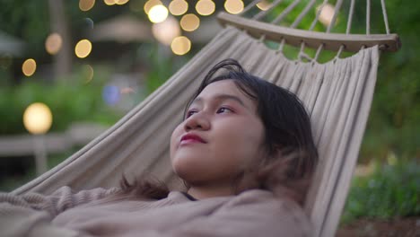 happy asian (indonesian) girl resting, sleeping, waking up, and smiling on a hammock.