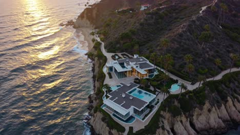 golden hour illuminating shimmering ocean waves near luxurious cliffside residence, featuring infinity pool and swaying palms overlooking dramatic california coastal landscape