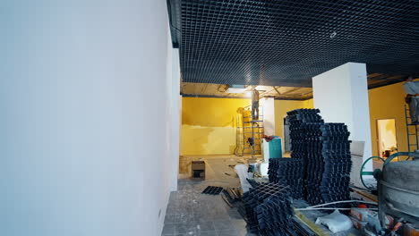 men install the equipment and decor on the ceiling of the big room. builders stand on the scaffold towers working.