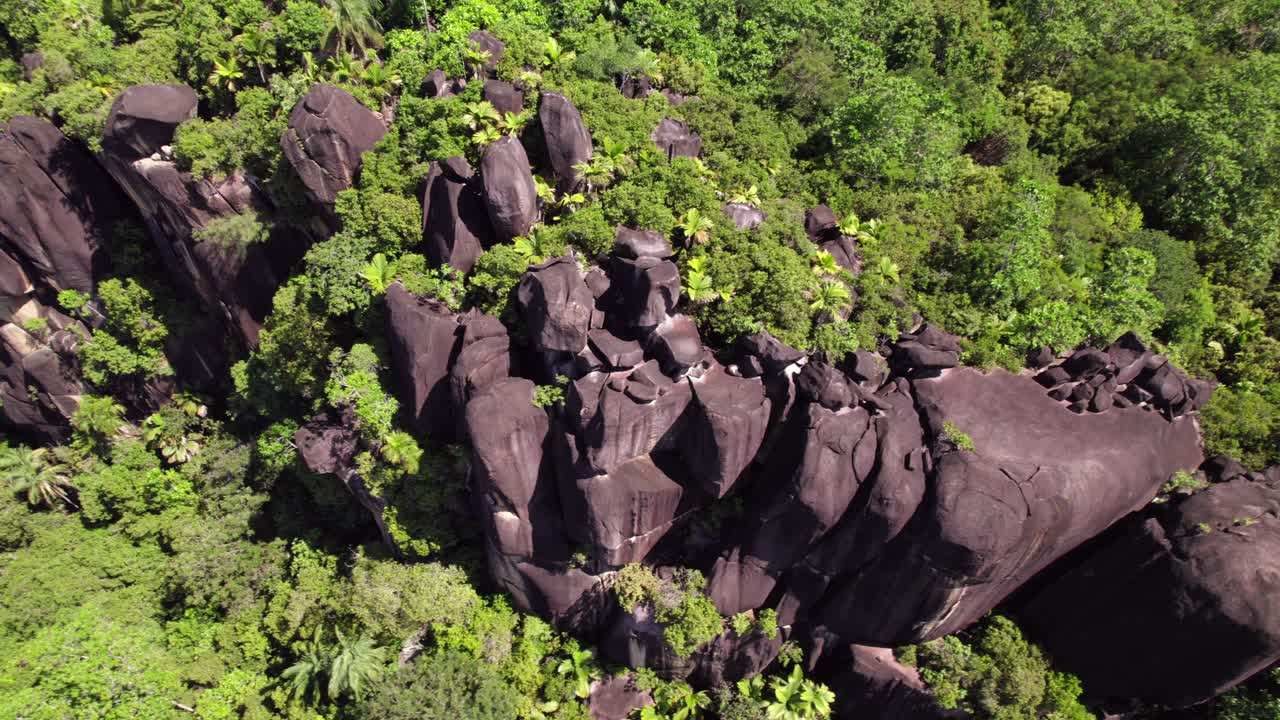 imágenes de drones de enormes piedras de granito en la cima de la montaña cerca de la playa, rodeadas de árboles, mahe seychelles 30 fps