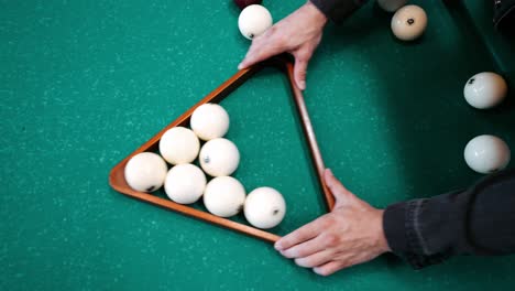 caucasian male racking white balls in triangular rack in a russian pyramide billiard