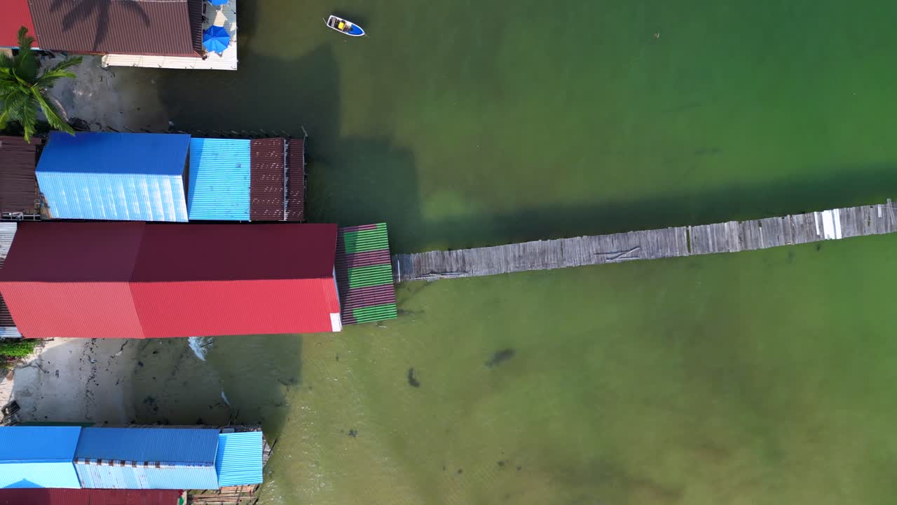 koh rong island in Cambodia, showing colorful stilt houses, piers and fishing boats in turquoise water. Spectacular aerial view flight ascending drone
