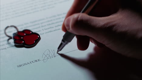 disparo en ángulo bajo de una mano caucásica femenina firmando un documento, con etiqueta de mascota