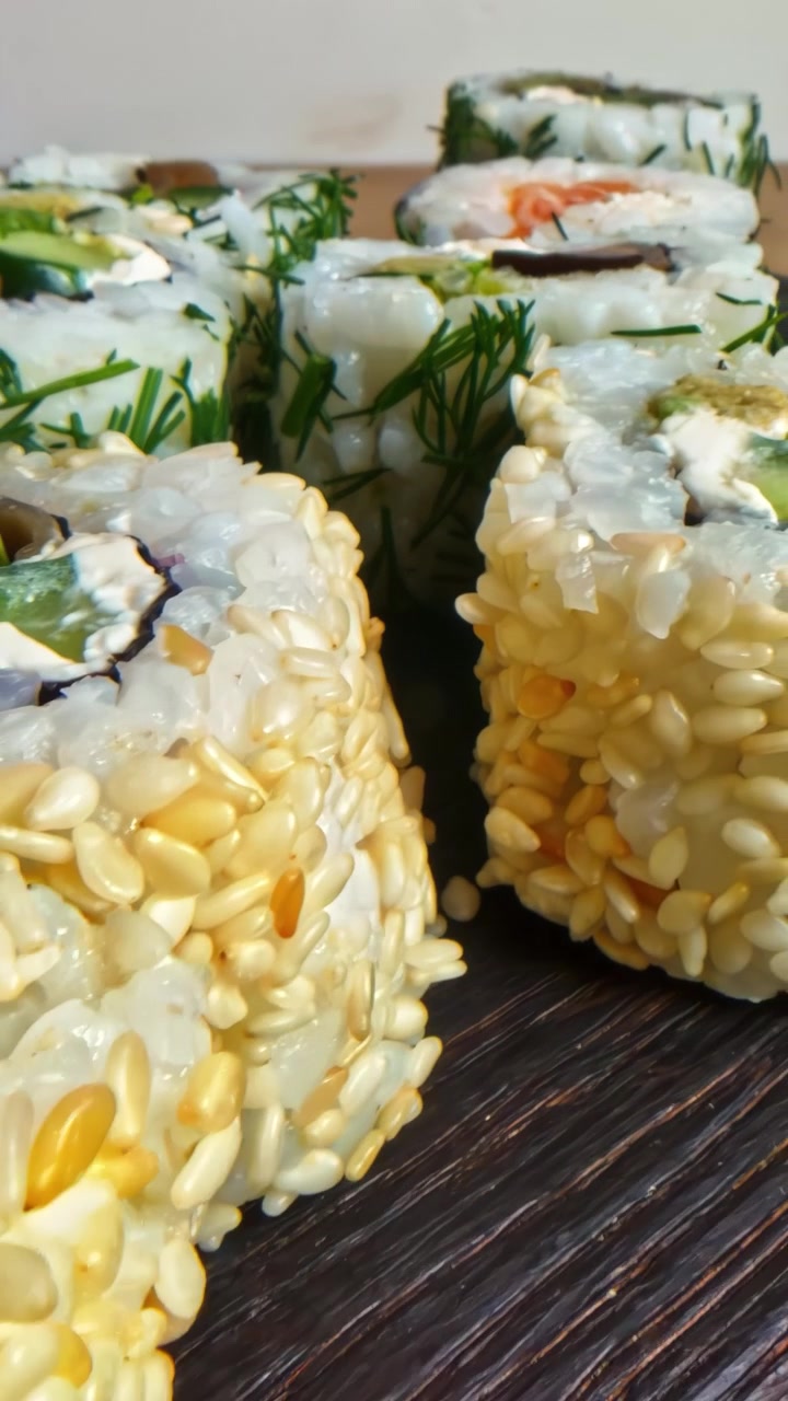 Panoramica verticale fluida e a mano di deliziosi e salutari rotoli di sushi freschi ricoperti di aneto verde.
