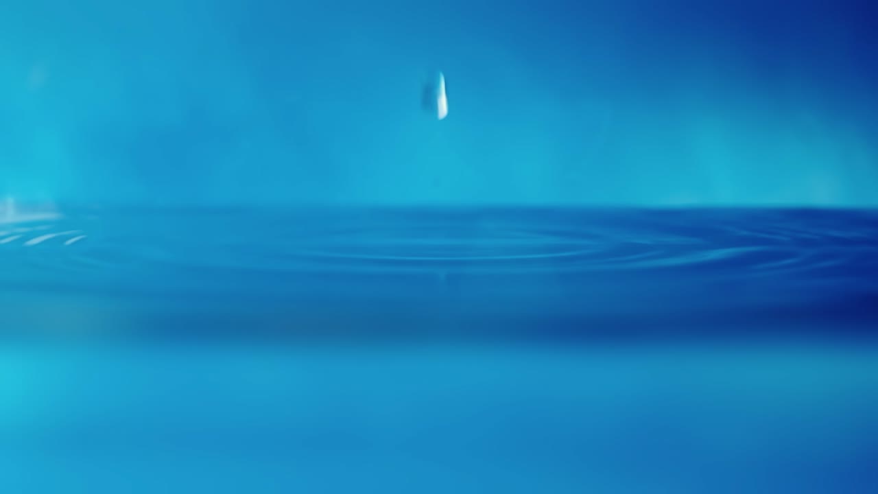 파란색 배경에 떨어지는 물방울과 함께 물 표면의 느린 모션 4k 비디오.