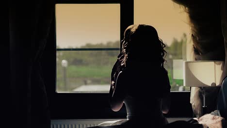 young beautiful girl sits in front of a window bride silhouette