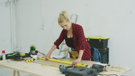 mujer usando un nivel de burbuja en el escritorio del taller