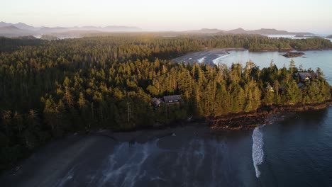 drone aerial view of isolated lodge in green forest by beach and pacific ocean