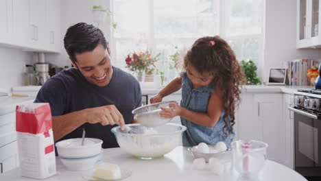 Hispanic-father-and-his-young-daughter-preparing-cake-mix-in-their-kitchen,-close-up