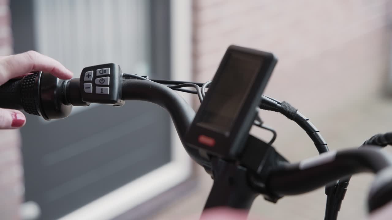 cierre del manillar de una bicicleta eléctrica mientras un hombre y una mujer descubren cómo encenderla usando los controles del manillar