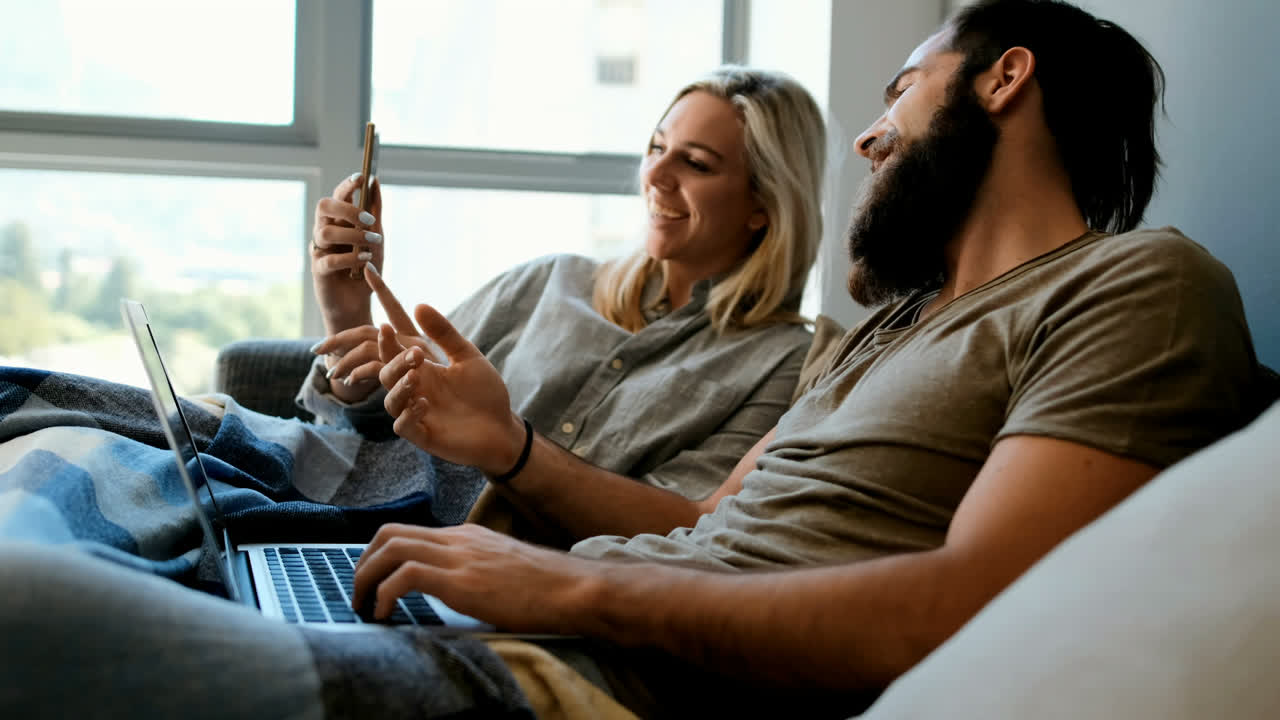Couple using mobile phone and laptop in living room 4k