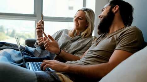 couple using mobile phone and laptop in living room 4k