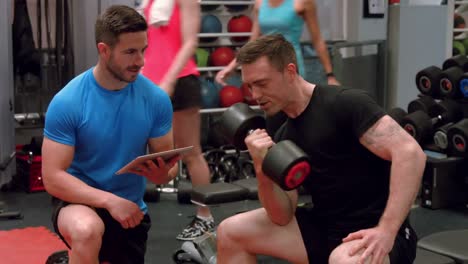 man lifting dumbbell with trainer