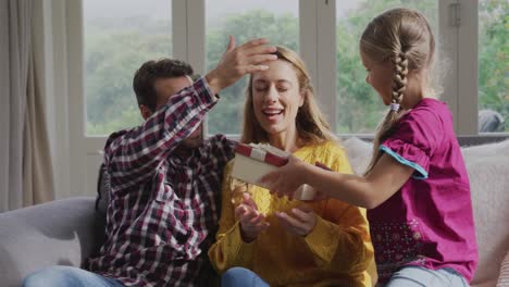 hija dando un regalo a su madre en el sofá en una casa cómoda 4k
