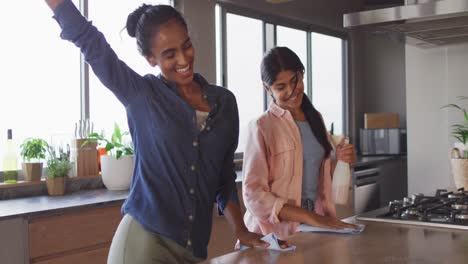 video of happy diverse female friends cleaning house and dancing