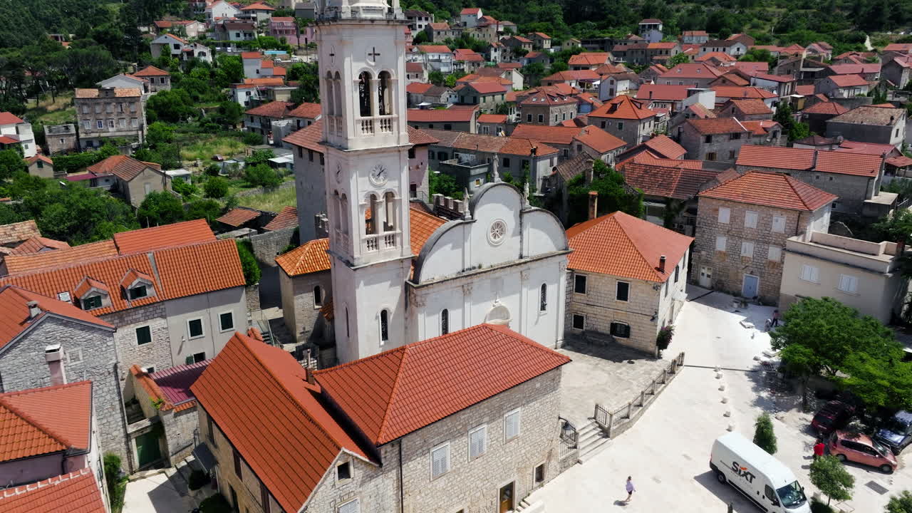 Fortified Church Of St. Mary’s Assumption Surrounded By Residential Houses In Jelsa, Hvar Island, Croatia. - aerial shot