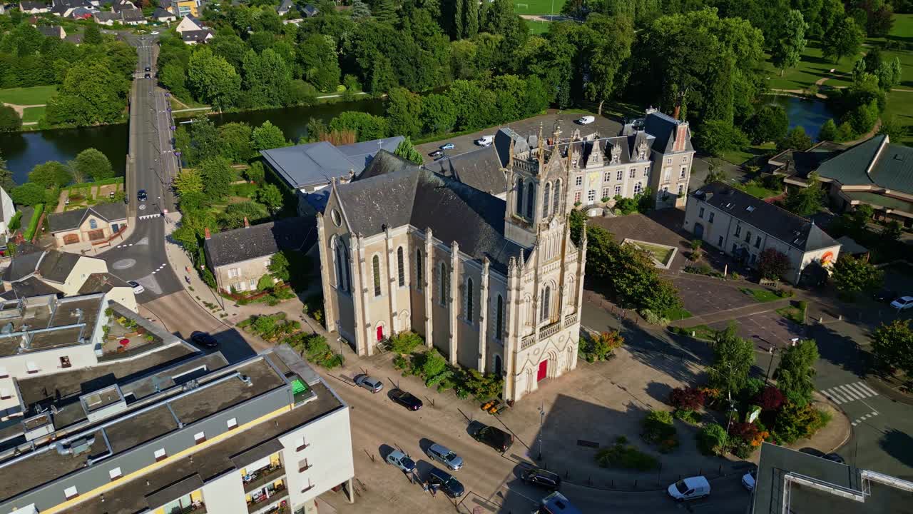 Panning drone movement near the historic Saint-Pierre Church of Chenillé-Changé aka Église Saint-Pierre de Chenillé-Changé, Changé, Mayenne, France