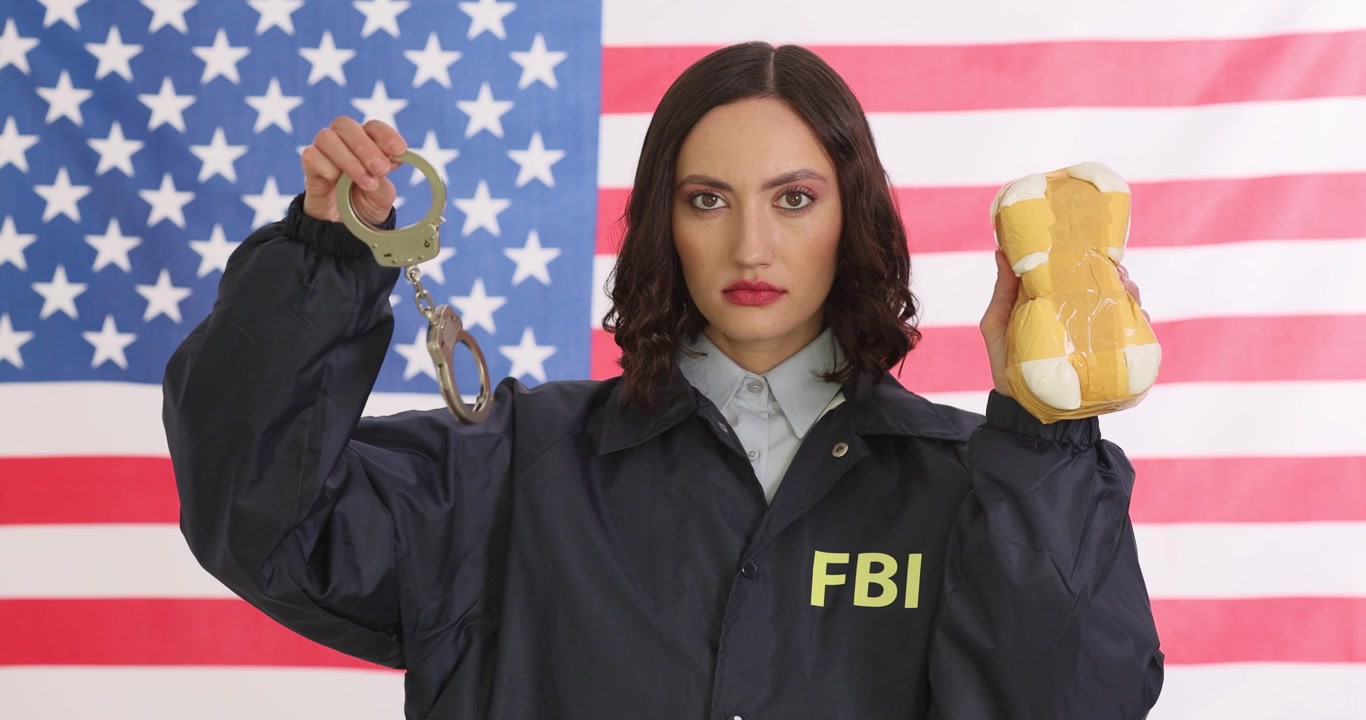 Agente donna dell'FBI tiene una confezione di droga e un paio di manette.