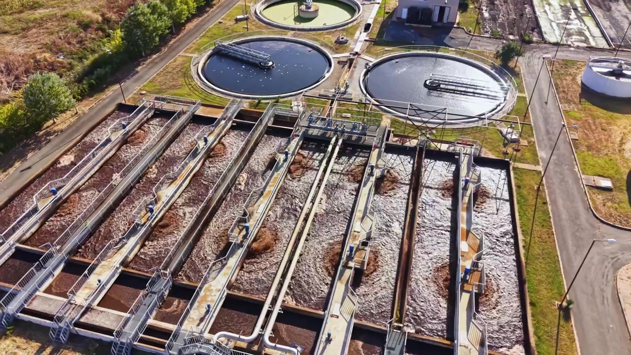 Water treatment facility with multiple large tanks and processing areas under sunlight