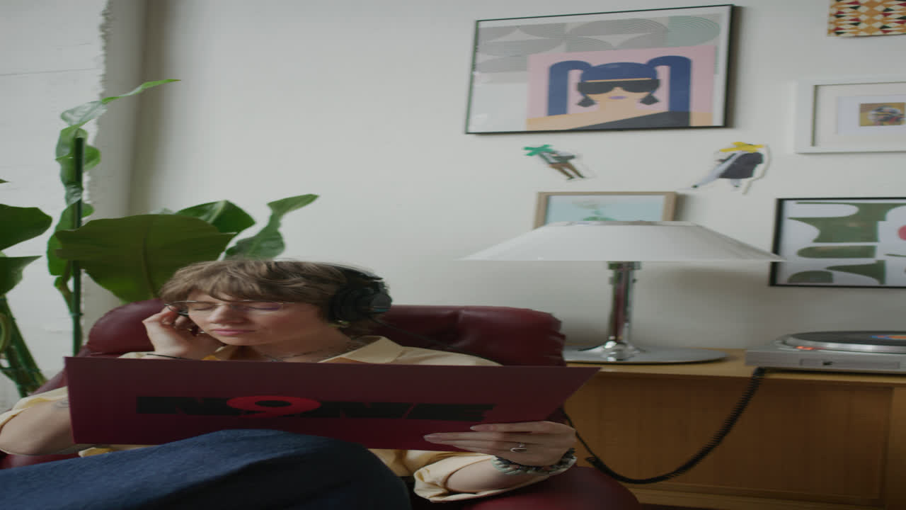 Giovane donna con le cuffie che si gode la musica e legge la copertina di un vinile
