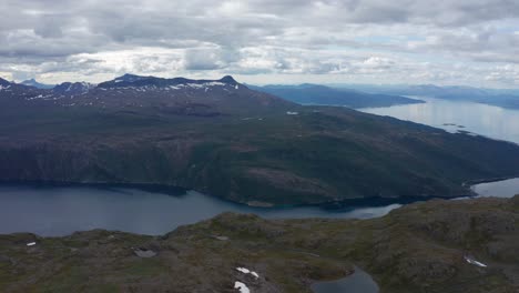 Drone-shot-of-northern-Norway-landscape-with-mountains,-lakes-and-fjord-and-dramatic-sky