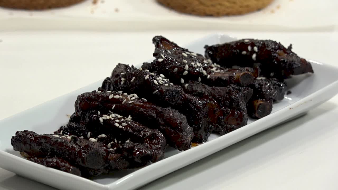 A backyard barbecue features perfectly smoked beef ribs with a rich, caramelized glaze. Friends gather to enjoy great food and lively conversation on a sunny afternoon.
