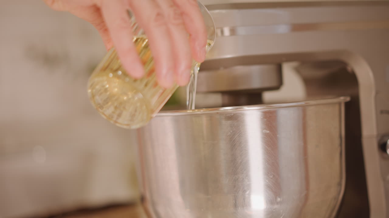 Profumo autunnale di dolci. Un fornaio casalingo mescola gli ingredienti della zucca. Versa l'olio nella ciotola per l'impasto fatto in casa della torta di zucca. Il fornaio prepara l'impasto della torta di zucca con spezie calde in un'accogliente cucina autunnale.