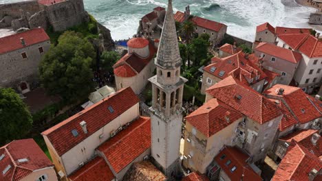 saint john the baptist church bell tower amid red roofed old town buildings in budva, montenegro