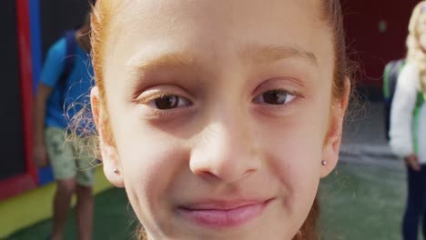 Porträt-Eines-Glücklichen-Kaukasischen-Schulmädchens,-Das-Auf-Dem-Spielplatz-In-Die-Kamera-Blickt